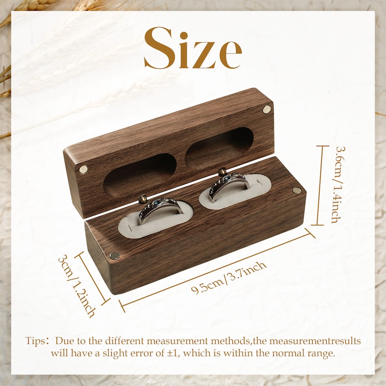 May include: A wooden ring box with two compartments for holding rings. The box is 9.5 cm long, 3.6 cm tall, and 3 cm wide. The box is made of dark brown wood and has a smooth finish.
