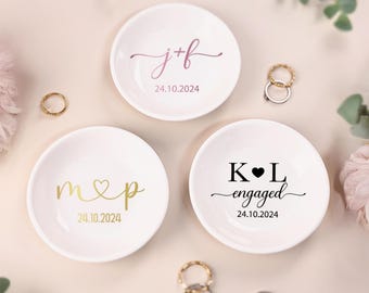 Pode incluir: Três pratos de cerâmica branca para anéis com letras douradas e pretas. Os pratos são personalizados com iniciais e a data "24.10.2024". Um prato diz "j+f", outro diz "m&p" e o terceiro diz "K&L noivos".