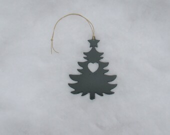 May include: A black metal Christmas tree ornament with a heart cut out in the center. The ornament is hanging from a string and is on a white snowy background.