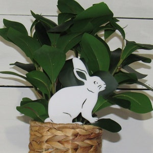 May include: White rabbit cutout in a woven basket with green leafy plants.