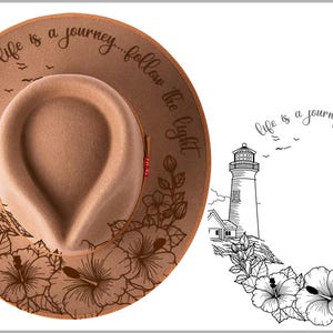 May include: A tan fedora hat with a lighthouse and floral design. The hat features the phrase "Life is a journey... follow the light" around the brim. The hat has a brown brim and a tan crown.