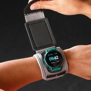 Könnte beinhalten: Ein graues und schwarzes Armband mit einem daran befestigten grün-schwarzen Fitness-Tracker. Der Tracker zeigt die Zeit 09:42 und das Datum Sa, 14. März.