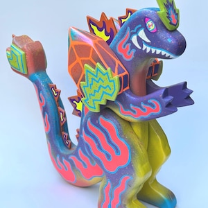 May include: A colorful, stylized dragon figurine with a vibrant design. The sculpture features a purple body, yellow legs, and a tail with blue and red flame accents. The dragon has a detailed head with white teeth and a crown.