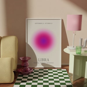 May include: A room scene featuring a framed Libra zodiac sign art print with a pink and purple gradient. A green and white checkered rug sits on a wooden floor. A pink lamp and a small green table are also visible.