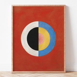 May include: A framed abstract painting with a red background and a large circle in the centre. The circle is made up of concentric rings of black, white, pink, yellow, and blue.