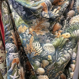 Peut inclure: Un tissu orné d'un motif marin. Le motif présente des coraux, des coquillages et diverses plantes marines dans des tons de vert, de bleu et d'orange. Le tissu est drapé, révélant sa texture et ses détails.