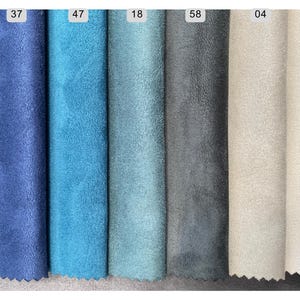 May include: A collection of fabric swatches in various shades of blue, gray, and beige. The swatches are arranged vertically, showcasing a range of colors from deep navy to light cream. Each swatch is labeled with a number.