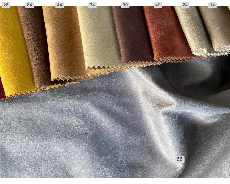 May include: A selection of fabric swatches in various colors, including yellow, brown, and burgundy. The swatches have a textured appearance and are arranged in a row. A large piece of blue fabric is in the foreground, with the number 66 in the corner.