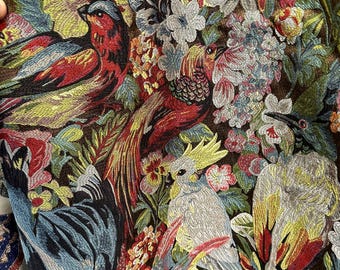 May include: Close-up of a richly embroidered fabric featuring a vibrant tapestry of colorful birds and floral elements. The design showcases a variety of birds in shades of red, blue, yellow, and green, set against a dark brown background.
