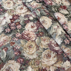 May include: A floral tapestry featuring a dense pattern of roses in shades of cream, burgundy, and muted green. The fabric has a woven texture, with the flowers and foliage overlapping. The overall effect is a vintage, romantic aesthetic.