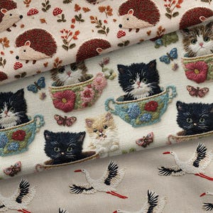 May include: Close-up of three different fabrics with embroidered designs. One features hedgehogs, mushrooms, and foliage. Another showcases kittens in teacups with butterflies. The third displays flying storks.