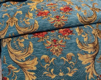 May include: Close-up of a teal fabric with a detailed gold and red floral pattern. The fabric has a textured appearance with a repeating design of stylized flowers and ornate scrollwork, creating a luxurious look.