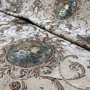 May include: Beige fabric with a detailed baroque design. The fabric features ornate gold and brown scrollwork, floral accents, and oval medallions with floral paintings. The overall pattern is symmetrical and luxurious, suitable for upholstery or drapery.