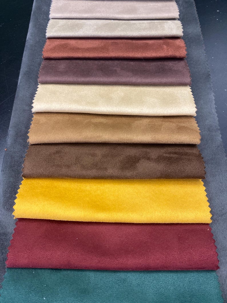 May include: A collection of fabric swatches in various colors, including beige, brown, and burgundy. The samples are arranged in a vertical stack, showcasing the different textures and shades of the material. The swatches are likely for upholstery or interior design.