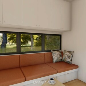 Puede incluir: Vista interior de una peque&ntilde;a sala de estar con un sof&aacute; naranja empotrado debajo de una ventana grande. Dos cojines decorativos descansan sobre el sof&aacute;. Hay armarios blancos encima de la ventana y una escalera de madera conduce a un nivel superior.