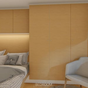 Puede incluir: Interior de dormitorio con armarios de madera clara y cabecero empotrado con un brillo c&aacute;lido. La cama est&aacute; hecha con ropa de cama gris y blanca, y una silla blanca est&aacute; cerca de una ventana con una persiana de tono neutro. La palabra "BEDROOM" es visible.