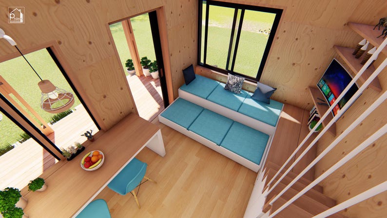 Puede incluir: Vista interior de una casa peque&ntilde;a moderna con paneles de madera clara. Incluye una peque&ntilde;a zona de cocina con mesa y sillas, una zona de estar integrada con cojines azules y una escalera. Un televisor est&aacute; montado en la pared.