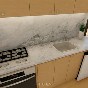 Puede incluir: Una cocina moderna con gabinetes de madera clara, una encimera de m&aacute;rmol y electrodom&eacute;sticos de acero inoxidable. Incluye una estufa de gas, un fregadero y un peque&ntilde;o refrigerador. Una computadora port&aacute;til y una taza de caf&eacute; est&aacute;n en una mesa cercana.