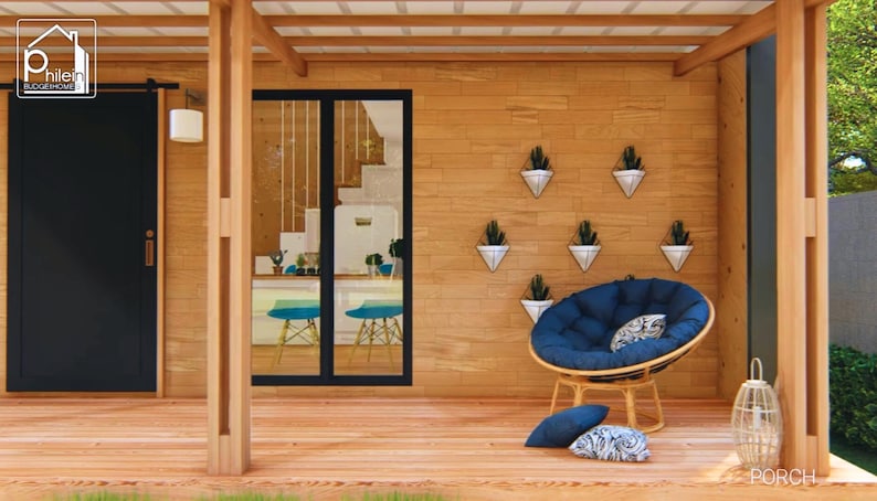 Puede incluir: Un porche exterior acogedor con una terraza y paredes de madera. Una puerta negra est&aacute; a la izquierda, y una puerta de cristal revela un vistazo del interior. Una silla papasan azul con cojines se encuentra cerca de la pared con macetas colgantes.