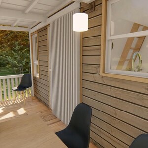 May include: Exterior view of a small cabin with a porch. The cabin features wooden siding, a white railing, and a black chair. A bonsai tree sits in a wooden planter. A window reveals a kitchen with a sink and a ladder.