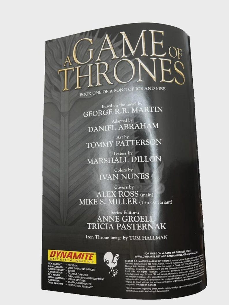 Może przedstawiać: Okładka książki "Gra o Tron" z tytułem w złotych literach. Wymienia George'a R.R. Martina jako autora i innych wsp&oacute;łtw&oacute;rc&oacute;w. Logo Dynamite Entertainment jest widoczne na dole. Część serii "Pieśń Lodu i Ognia".