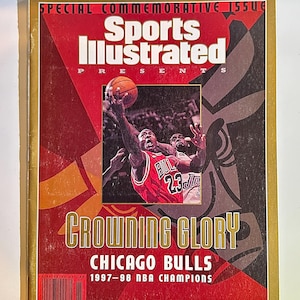 May include: Sports Illustrated magazine cover featuring a photo of Michael Jordan in a red Chicago Bulls jersey with the number 23, holding a basketball. The cover text reads "CROWNING GLORY" and "CHICAGO BULLS 1997-98 NBA CHAMPIONS".
