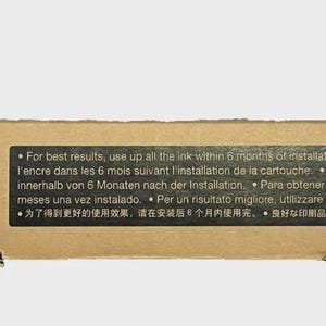 May include: A cardboard box for an Epson ink cartridge. The box has the Epson logo and text in multiple languages. The box also has international shipping symbols and a black label with usage instructions.