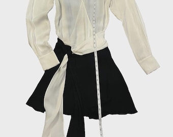May include: A two-tone dress with a white top and a black skirt. The top has long sleeves and black shoulder accents. A white sash wraps around the waist, and a tag is attached. The dress is approximately 50 inches long.