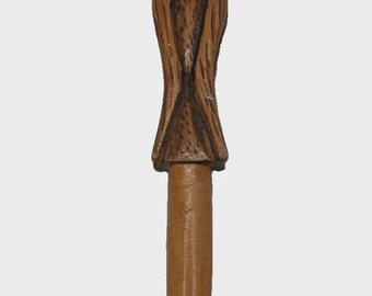May include: A brown wooden pen featuring a hand-carved topper shaped like a horned figure with a long beard and detailed facial features. The body of the pen is smooth and cylindrical, tapering toward the tip, showcasing natural wood grain.