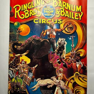 May include: A vintage Ringling Bros. and Barnum & Bailey Circus souvenir program cover. The cover is red with the circus name in large, colorful letters. The illustration features an elephant, tiger, clown, and acrobats.