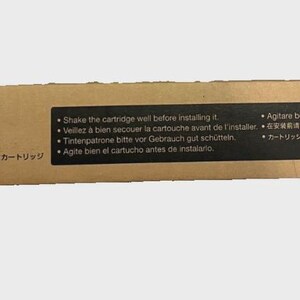 May include: A brown cardboard box with the Epson logo and the words "EXCEED YOUR VISION." The box contains an ink cartridge and instructions in multiple languages, including English, French, German, Spanish, Italian, and Japanese.