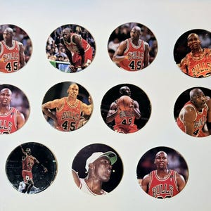May include: A collection of ten round trading cards featuring images of basketball players wearing red and black uniforms with the word "Bulls" and the number "45" on their jerseys.