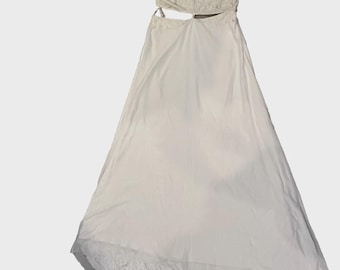 May include: A white, two-piece dress with a cut-out design. The top features short, ruffled sleeves and a sequined bodice. The skirt is long and flowing, with a layered hemline. The dress appears to be made of a lightweight fabric.