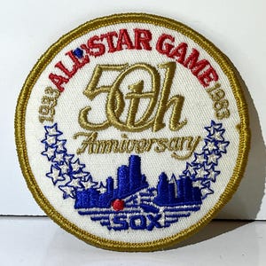 May include: A circular embroidered patch commemorating the 50th Anniversary of the 1983 All-Star Game. The patch features text in red and gold, a blue skyline, and the word "SOX". The patch is trimmed with gold thread.