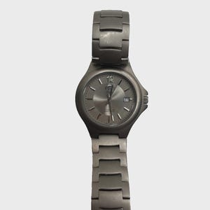 May include: A titanium wristwatch with a silver dial and matching strap. The watch has a date display and luminous hands. The watch is a classic design, suitable for everyday wear. The watch strap is approximately 20 cm long.