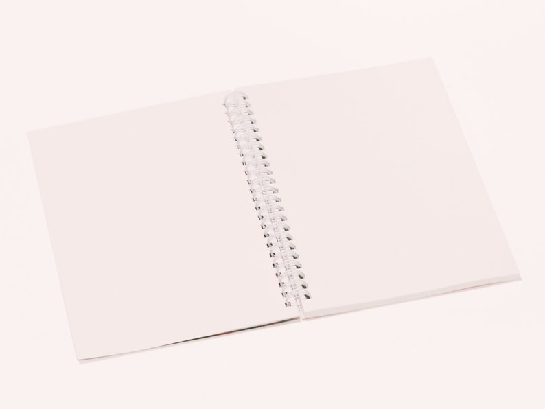 May include: An open, spiral-bound notebook with blank white pages. The notebook is lying flat on a white surface, with the pages spread open to reveal the clean, unused paper. The spiral binding is visible along the spine.