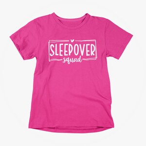 May include: Pink t-shirt with white text that says "Sleepover Squad" with a small heart above the word "Sleepover".