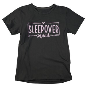May include: Black t-shirt with a pink graphic that says "Sleepover squad" with a small pink heart above the text.