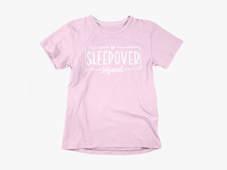 May include: A pink t-shirt with a white graphic that says "Sleepover Squad" with a heart above the text.