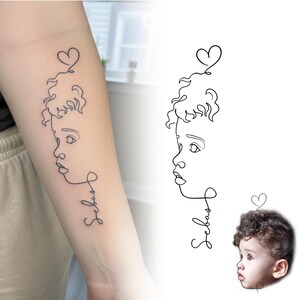 Fine line tattoo on arm next to original toddler photo. Custom tattoo design from photo and minimalist baby face tattoo commission.