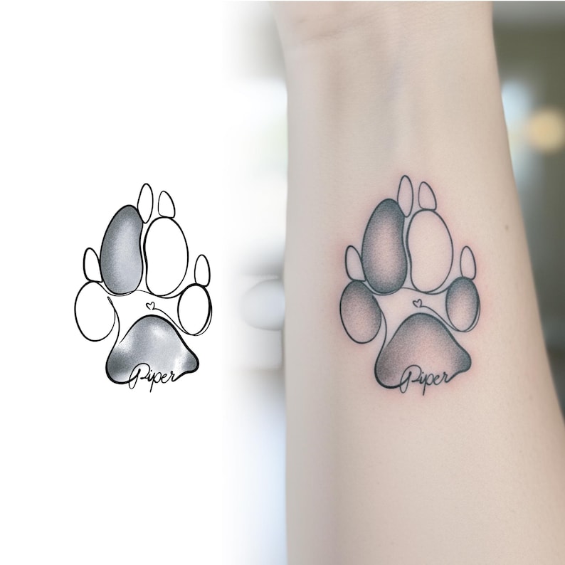 Dog paw print line art tattoo on wrist next to a realistic ink shading. Meaningful pet memorial tattoo design from photo.