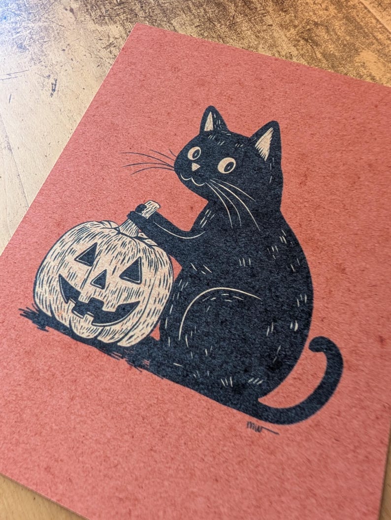 May include: A black cat illustration with a carved pumpkin on a reddish-orange background. The cat is sitting and appears to be holding the pumpkin. The pumpkin has a carved face. The artwork has a vintage, hand-drawn style.