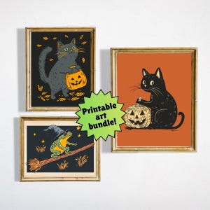 May include: Three framed Halloween art prints. One shows a grey cat with a pumpkin bag, another a black cat with a pumpkin, and the third a frog on a broom. The prints are in gold frames, with the text "Printable art bundle!"