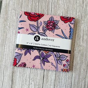 May include: A bundle of 42 fabric squares, each 12.7 cm x 12.7 cm, displaying a floral design with red roses, purple leaves, and blue details on a pink backdrop. The fabric is 100% cotton. The label reads "Perfect Day by Libs Elliott."