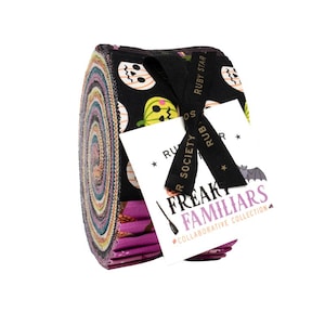 May include: A jelly roll of fabric strips featuring a black background with orange and green pumpkin patterns. A black ribbon tied around the roll holds a white tag printed with the text Ruby Star Society Freaky Familiars Collaborative Collection.