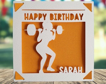 May include: A white card with a yellow background and a cutout of a person lifting weights. The card says "Happy Birthday Sarah".