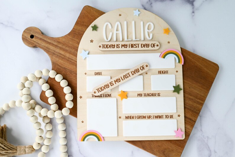 May include: Wooden school memory board with the name "CALLIE" at the top. The board includes spaces for "DATE", "HEIGHT", "THINGS I LOVE", "MY TEACHER IS", and "WHEN I GROW UP, I WANT TO BE". Decorative stars and rainbows are also included.