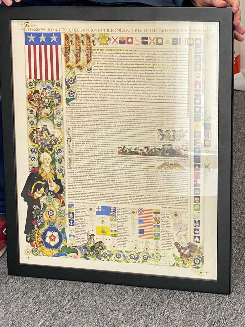May include: A framed print of the Declaration of Independence, a historical document signed by the founding fathers of the United States of America. The document is surrounded by decorative floral borders and includes a depiction of the American flag.