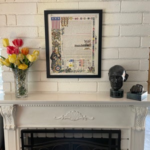 May include: A framed print of the Declaration of Independence with a decorative border. The print is hanging on a white brick wall above a white fireplace with a black metal grate.