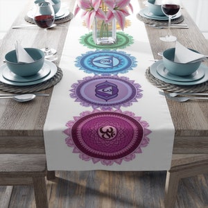 May include: White table runner with a colorful mandala design featuring the seven chakras. Each chakra is represented by a different color and symbol. The runner is perfect for adding a touch of spirituality to your dining table.
